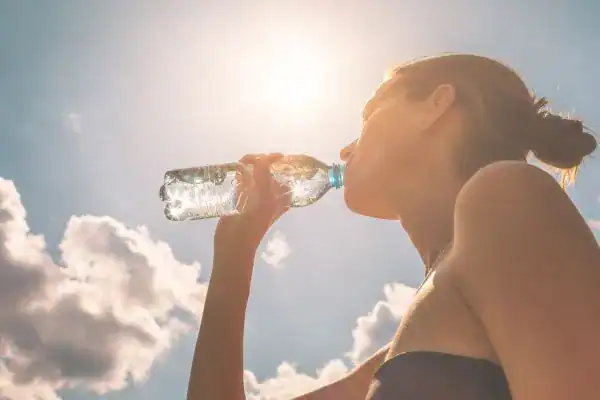 Image of woman drinking water to hydrate Witley after run.