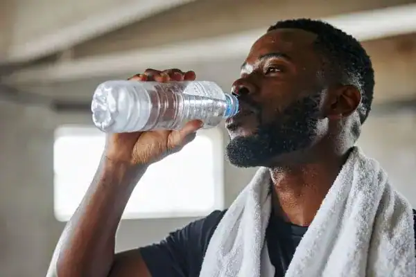 Image of man drinking water to improve hydration Witley after work out.